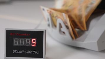 elektronisk räknare med tal ändring snabbt. kontanter räkning maskin räknas femtio euro räkningar bunt på bakgrund i fläck. video