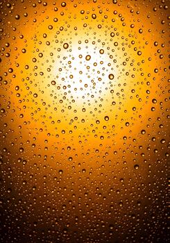 Golden rain drops on glass with bright light reflecting through them creating a vibrant texture perfect for backgrounds and abstract designs representing purity and freshness photo