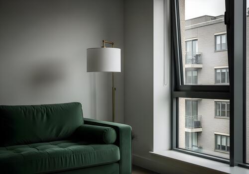 Interior view of a modern living room with a plush green sofa floor lamp and an open window showing an apartment building creating a cozy atmosphere photo