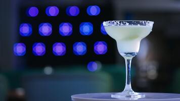 glas bägare på de liten roterande tabell. ljus dryck med en bit av kalk inuti. stänga upp. suddig bakgrund. video