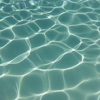 Sunlight reflecting and creating patterns on the surface of a turquoise swimming pool creating a sense of calmness and inviting relaxation for a summer getaway vacation photo