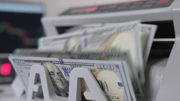 anteckningar med benjamin Franklin porträtt falla på de hållare av kontanter räkning maskin. stänga upp. suddig bakgrund. video