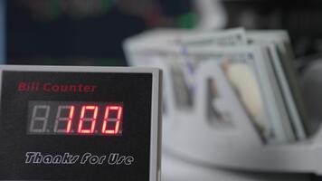 rosso figure mutevole velocemente su il schermo di conto contatore. vicino su. dollari essere contato a fondale nel sfocatura. video