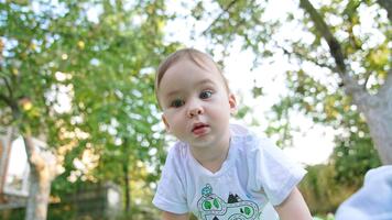 curioso poco bambino ragazzo esplorando il telecamera e battimani di esso. Basso angolo Visualizza. sfocato sfondo. video