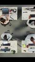 vertikal topp ner se av företag människor samlade in runt om bärbara datorer arbetssätt på projekt uppgifter för utveckling. kontor miljö främjar synergi, lagarbete och insikt genom analyser. kamera a. video