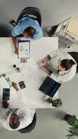 vertikal topp ner se zoom i av doktorer team i en samarbete möte diskuterar terapi, diagnostik och klinisk samordning. modern personal fokuserar på kommunikation och patient hälsa. kamera a. video