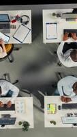 vertikal topp ner se zoom i av olika kollegor arbetssätt i modern kontor, fokusera på projekt planera, prestanda metrik och Rapportera delning. företag människor recension data för prognoser. kamera a. video