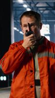 vertikal tekniker använder sig av walkie prat under jobb uppdrag i tillverkning anläggningen, som visar de grundläggande kommunikation nödvändig till klara av verktyg och maskineri. svetsning drift. kamera b. video