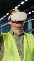 Vertical Employee uses VR headset to test 3D simulation concepts for heavy machinery in safety uniform, managing modern operation in factory facility. Professional workflow in warehouse. Camera B. video