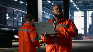 tekniker förvaltar drift förfaranden med handhållen bärbar dator, highlighting teknik ansvar och arbetskraft styrka medan han promenader runt om på de fabrik golv. verkstad tillverkning. kamera b. video