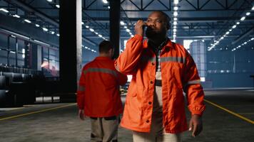 svart operatör samtal genom walkie prat och övervakning metall tillverkning Utrustning i verkstad, hantering professionell ansvar och teknik uppgifter involverad i växt drift. kamera a. video