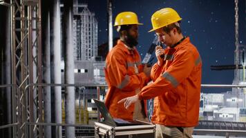 offshore borrning rigg ingenjör tala genom walkie prat med kollegor, övervakning olja extraktion system för effektivitet. påfrestande till minimera kol fotavtryck nivåer på plattform. kamera b. video