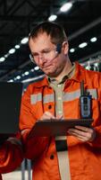 Vertical Colleagues use laptop and tablet to guide personnel during fabrication and production tasks, highlighting industrial labor and engineering. Operation of the manufacturing process. Camera B. video