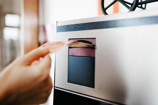 Hand inserting banknote into a cash machine, showcasing the transaction process, with a blurred background of a modern interior setting, emphasizing convenience and technology photo