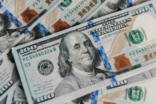 Close-up view of multiple hundred-dollar bills stacked together, showcasing intricate details of currency design, texture, and color, representing wealth and financial transactions photo