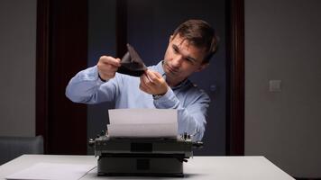 uomo seduta a un' scrivania con un' macchina da scrivere, guardare con preoccupazione in un vuoto portafoglio, simboleggiante finanziario lotta e mancanza di reddito per un' creativo professionale video