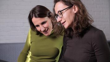Two professional women working together, focusing intensely on a laptop screen, engaging in a productive discussion, and analyzing data for a shared business project or remote work video