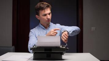Mens op zoek Bij zijn pols kijk maar terwijl werken Bij een bureau met een oud fashioned schrijfmachine, markeren concepten van tijd beheer, termijnen, en de druk van creatief werk video