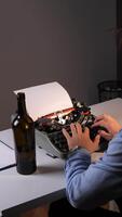 vertical Hands type on an old manual typewriter, creating a written story or document with a bottle and empty notepad beside it, symbolizing creativity, nostalgia, and journalistic work video