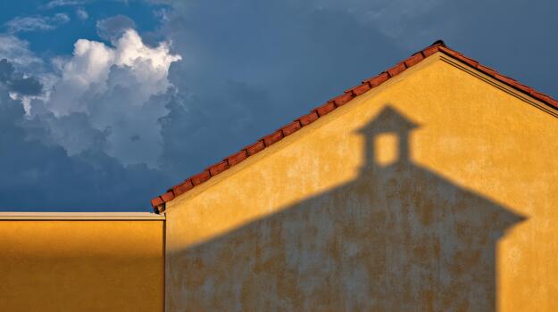 Sunset shadows cast by a yellow building under clouds photo