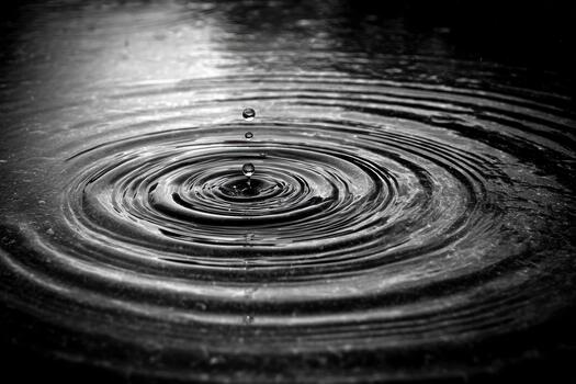 Water droplets create ripples on dark surface photo