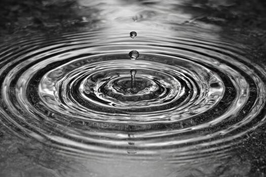 Water drop creates ripples in still water surface photo