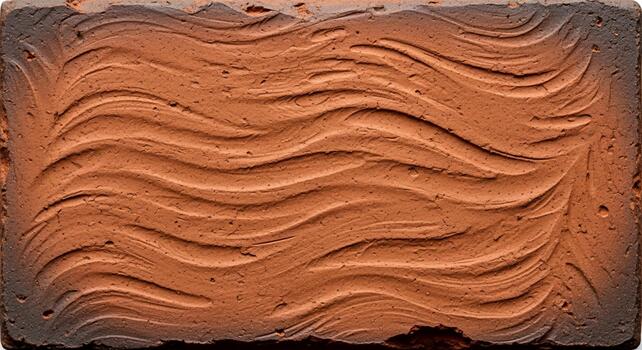 Close up view of a weathered terracotta brick with an embossed wavy pattern showcasing its rustic texture and earthy tones photo