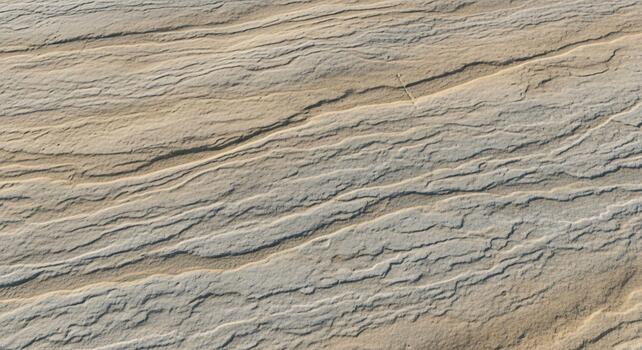 Close up textured surface of natural sandstone with subtle variations in earthy tones and layered striations creating a natural abstract pattern photo