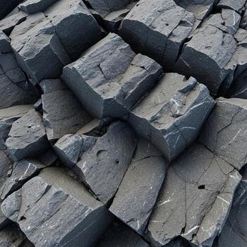 Close up view of a pile of rough dark gray angular rock fragments creating a textured background photo