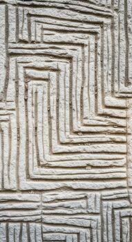 Intricate geometric maze like pattern carved into a textured stone surface creating a visually engaging abstract design photo