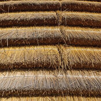 Close up view of a textured thatched roof showing layers of dry straw and natural fibers creating a rustic pattern photo