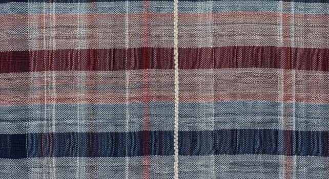 Close up view of a woven fabric with a plaid pattern featuring horizontal and vertical stripes in various colors and textures photo