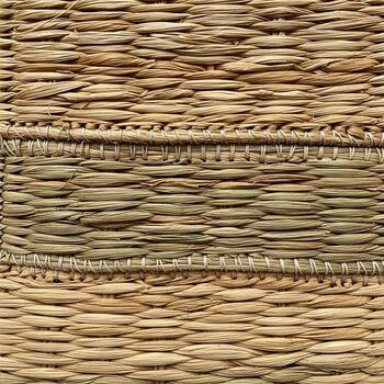 Close up textured background of woven natural straw mat with horizontal bands of varied color and weave patterns photo