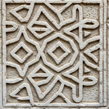 Intricate geometric pattern carved into stone with repeating diamond and abstract shapes photo