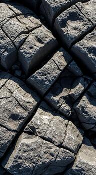 Close up view of weathered fractured rock formations with deep shadows highlighting their rugged texture and geometric patterns photo