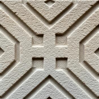 Intricate geometric pattern carved into light colored stone with repeating square and diagonal motifs photo