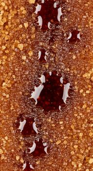 Close up macro view of dark red liquid droplets on a textured golden surface creating abstract patterns photo
