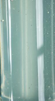 Abstract close up of translucent blue green liquid with subtle bubbles and light reflections creating a serene ethereal texture photo