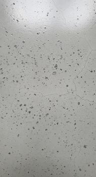Close up abstract texture of water droplets on a smooth reflective gray surface creating a blurred speckled pattern photo