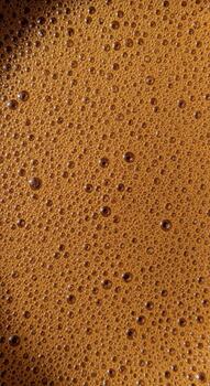 Close up abstract texture of rich brown coffee foam with small bubbles creating a unique pattern photo