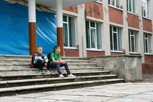 Two young students taking a break on the steps of a building, waiting before classes, sporting backpacks and casual clothes on a sunny day. photo