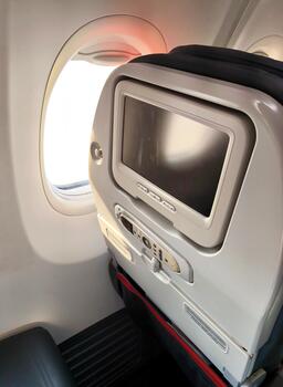 A view from inside the airplane cabin of the window and the back of the seat with a built-in monitor photo