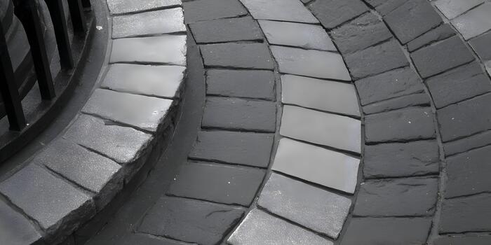 A close up view of a monochrome stone paved surface featuring light and dark grey rectangular blocks in a curving pattern photo