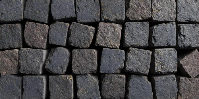A close up view shows a rustic pattern of dark grey and brown stone paving blocks with hints of yellow photo