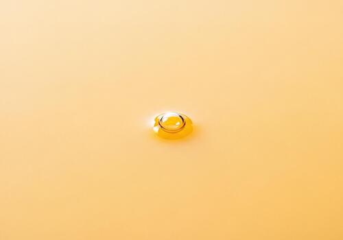 soltero dorado transparente soltar reflejando ligero en un suave amarillento líquido textura foto