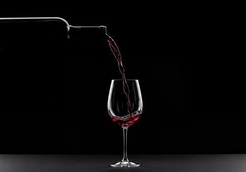 Dynamic Red Wine Pouring from Bottle into Elegant Glass Against a Dark Background photo