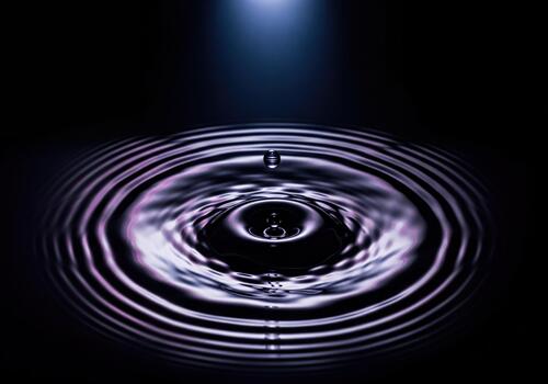 Mesmerizing Close Up of a Water Drop Creating Circular Ripples on a Dark Liquid Surface photo