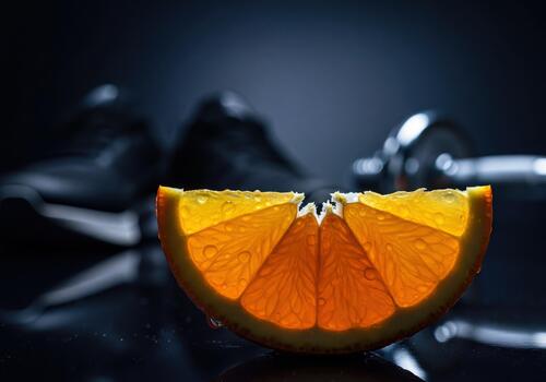 Fresh Juicy Orange Segment with Refreshing Water Droplets Illuminated on Dark Background photo