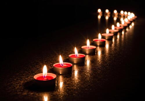 Serene Line of Flickering Red Tea Light Candles Reflecting on Dark Surface photo