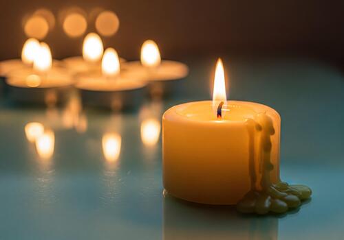 Warm Light of a Melting Wax Candle on Reflective Surface with Soft Bokeh Background photo